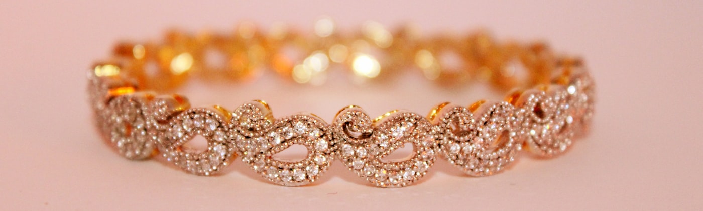 Rose gold diamond-set bracelet photographed on a soft pink background
